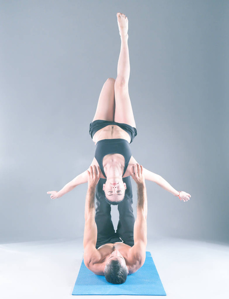 Young couple practicing acro yoga on mat in studio together. Acroyoga. Couple yoga. Partner yoga. - Фото, изображение