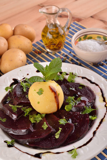 Prato branco com beterraba fatiada e batatas na mesa de madeira
  - Foto, Imagem