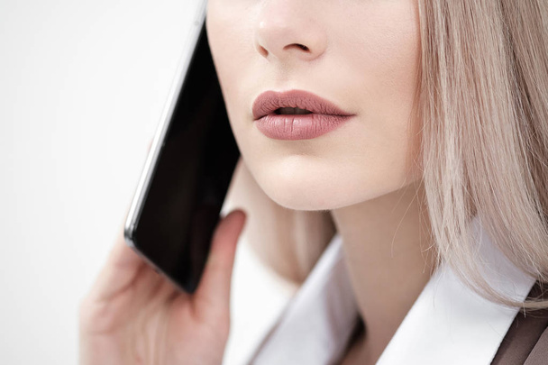 Close-up of the mouth and lips of a woman talking on a smartphone on a white background. - Photo, image