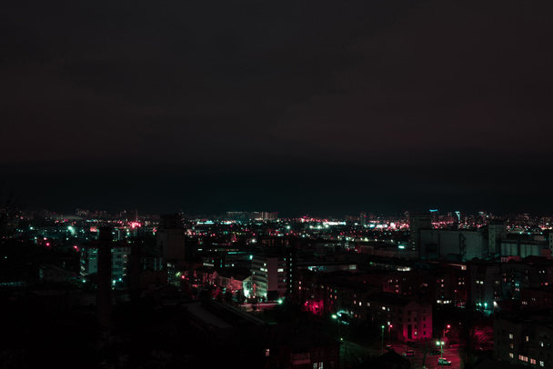 dark cityscape at night with multicolored illuminated windows - Fotoğraf, Görsel