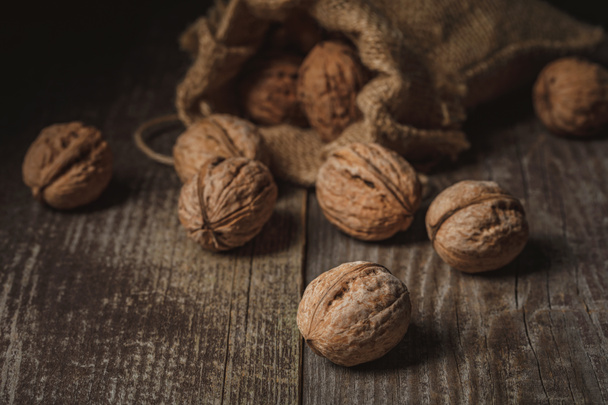 close up view of walnuts in sack on wooden background - Valokuva, kuva