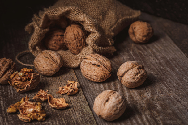 close up view of walnuts in sack on wooden background - Zdjęcie, obraz