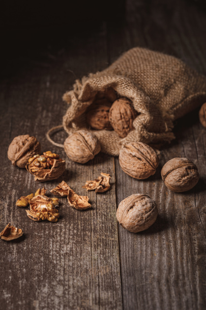 close up view of walnuts in sack on wooden background - Fotó, kép
