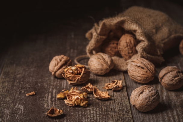 close up view of walnuts in sack on wooden background - Photo, Image