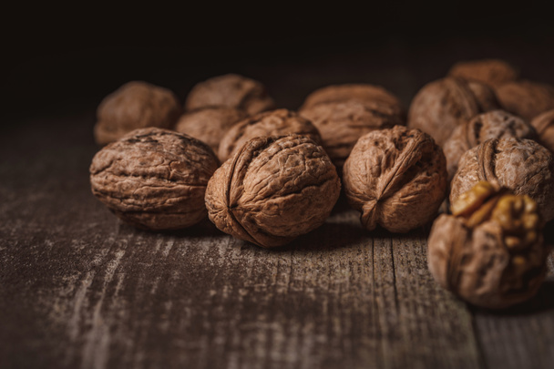 close up view of walnuts on wooden tabletop on black backdrop - Фото, зображення