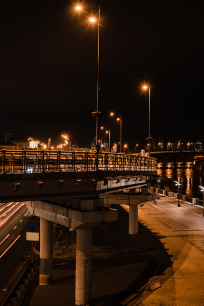 освещенный мост и дорога с яркими огнями ночью
 - Фото, изображение