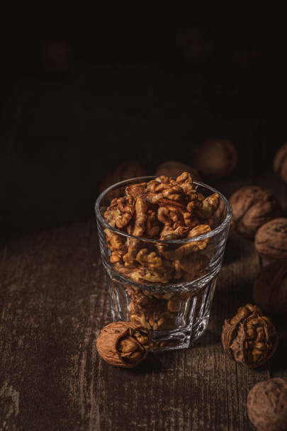 close up view of shelled walnuts in glass on wooden surface - Fotoğraf, Görsel