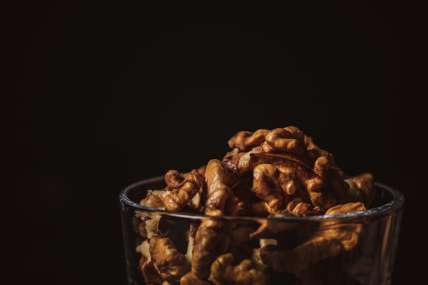 close up view of shelled walnuts in glass on black background - 写真・画像