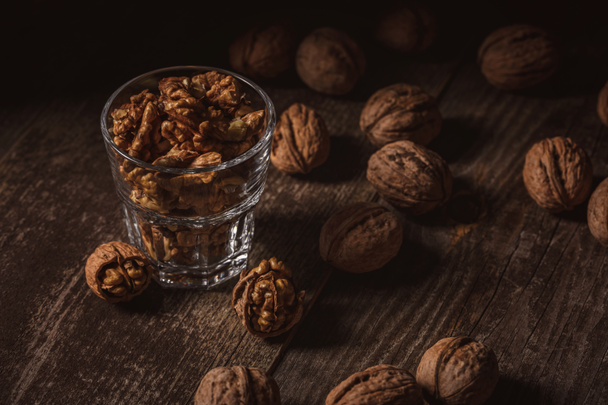 close up view of tasty shelled walnuts in glass on wooden table - Fotografie, Obrázek