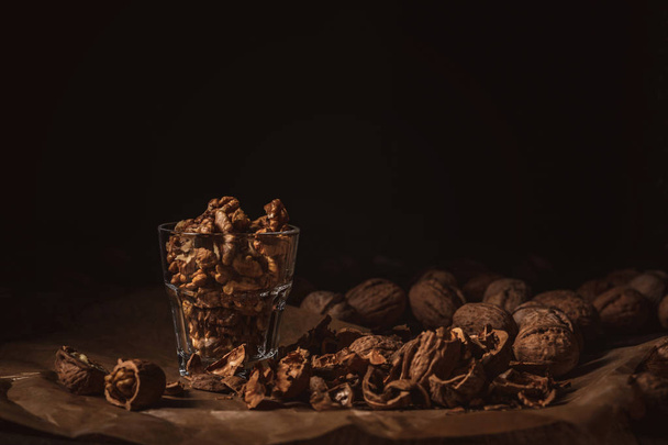 close up view of shelled walnuts in glass on black backdrop - Foto, Imagem