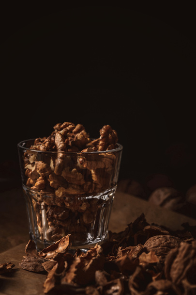 close up view of shelled walnuts in glass on black backdrop - Fotoğraf, Görsel