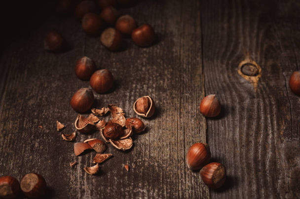 close up view of shelled hazelnuts and husk on wooden tabletop - Photo, Image