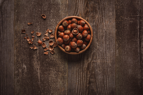 top view of hazelnuts in bowl on wooden tabletop  - Valokuva, kuva