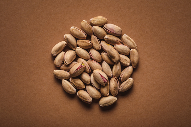 top view of pile of pistachio nuts on brown backdrop - Photo, Image