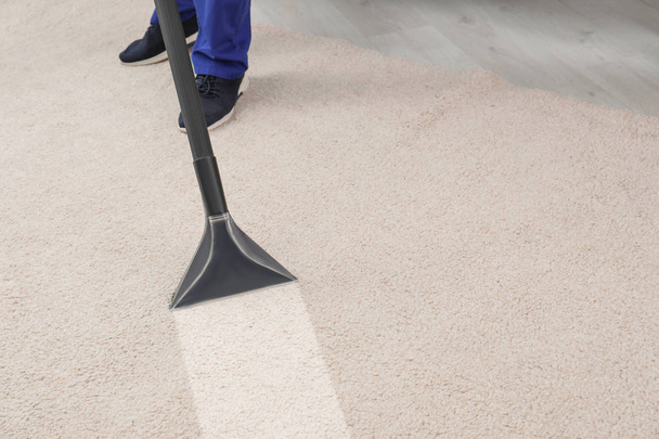 Man removing dirt from carpet with professional vacuum cleaner in room - 写真・画像