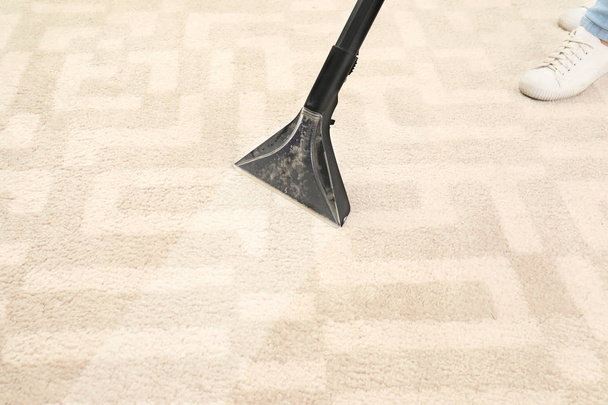 Woman removing dirt from carpet with vacuum cleaner in room - Foto, imagen