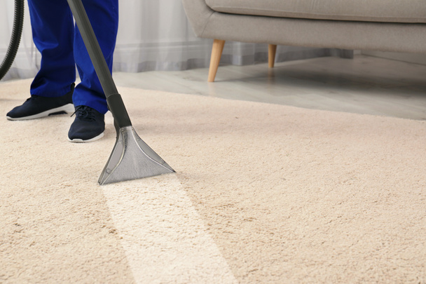 Man removing dirt from carpet with professional vacuum cleaner in room - Valokuva, kuva