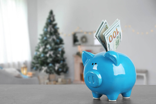Piggy bank with money on table in living room decorated for Christmas. Space for text - Фото, зображення