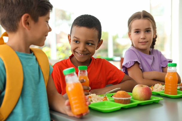 Children sitting at table and eating healthy food during break at school - Foto, afbeelding