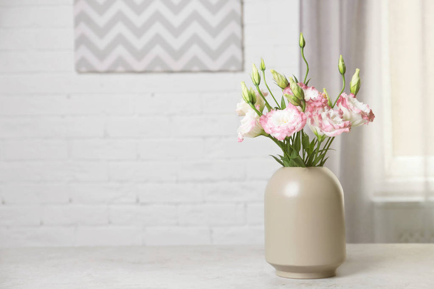 Beautiful flowers in vase and space for text on blurred background. Element of interior design - Φωτογραφία, εικόνα
