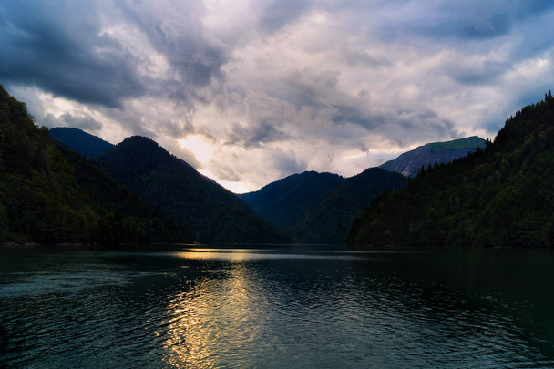 Lake in de bergen. Zonsondergang met weerspiegeling in het water. Onweerslucht in de hemel. Avond landschap. Schemering op het meer. - Foto, afbeelding