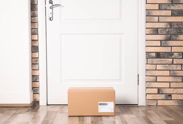 Cardboard parcel box on floor near apartment entrance. Mockup for design - Φωτογραφία, εικόνα