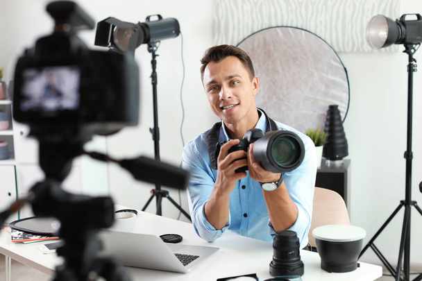 Male photo blogger recording video on camera indoors - Foto, imagen