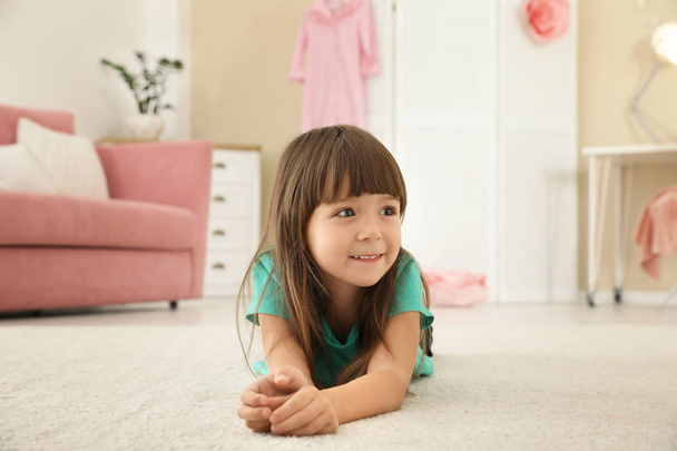 Carina bambina sdraiata sul tappeto a casa
 - Foto, immagini