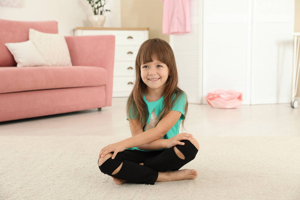 Cute little girl sitting on carpet at home - Foto, afbeelding