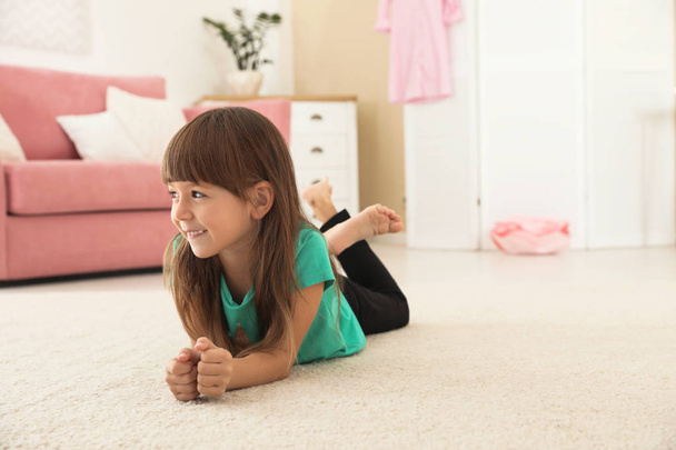 Cute little girl lying on carpet at home. Space for text - Fotoğraf, Görsel
