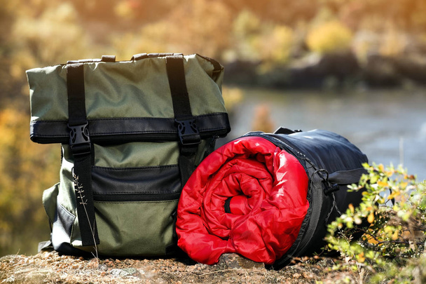 Backpack and sleeping bag on ground outdoors. Camping equipment - Fotografie, Obrázek