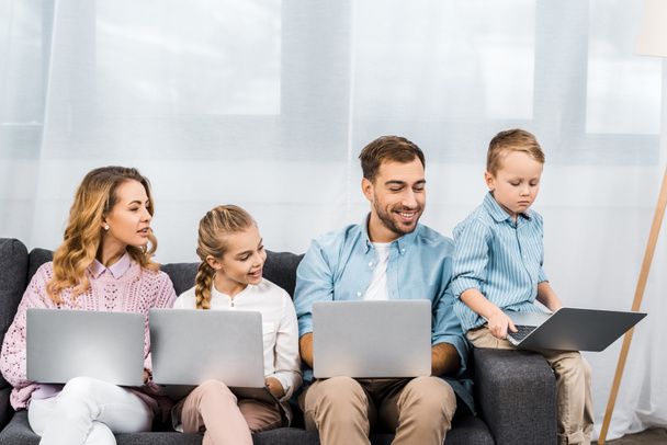 famiglia sorridente guardando computer portatile di ragazzo sconvolto
 - Foto, immagini