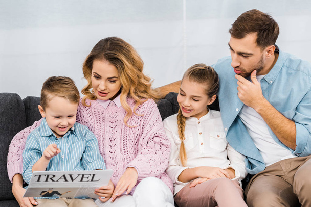 happy family sitting on sofa and reading travel newspaper in living room - Photo, Image