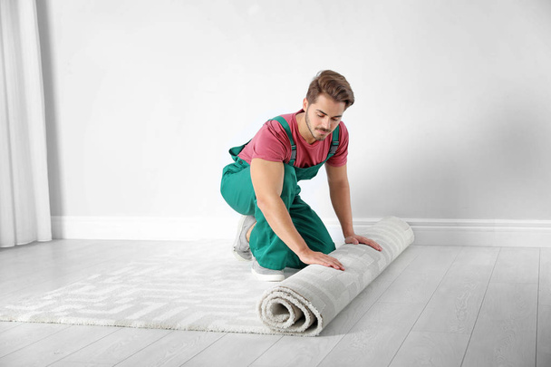 Man rolling out new carpet flooring indoors - Zdjęcie, obraz