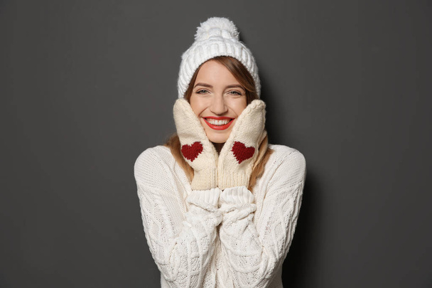 Beautiful young woman in warm sweater with hat and mittens on dark background - Foto, immagini