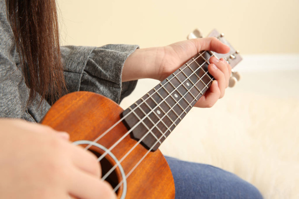 Little girl playing wooden guitar indoors, closeup - Foto, Imagen