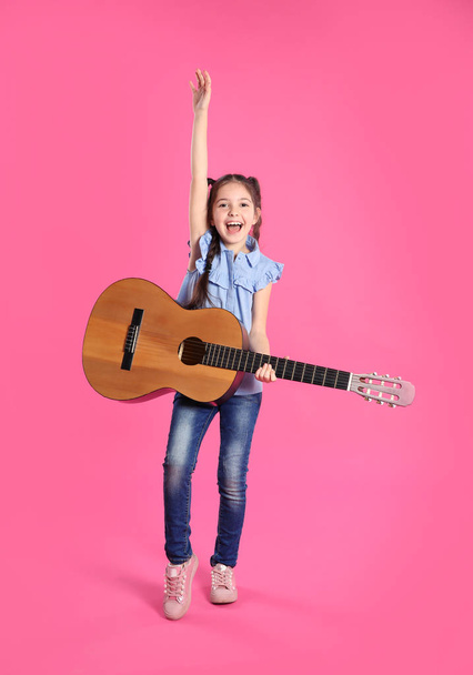 Cute little girl playing guitar on color background - Φωτογραφία, εικόνα