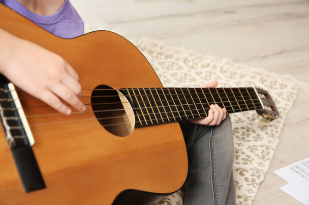 Little girl playing guitar on floor, closeup - Foto, afbeelding
