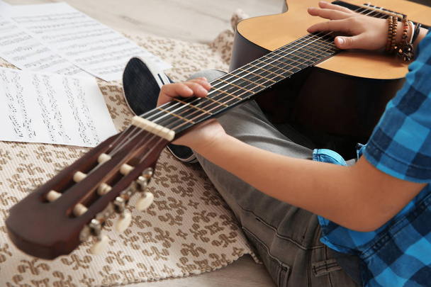 Little boy playing guitar on floor, closeup - Foto, imagen