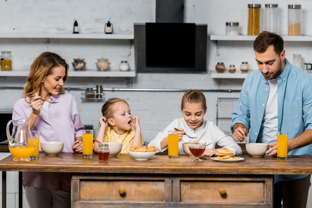 familia feliz comer gachas para el desayuno en la cocina
 - Foto, Imagen