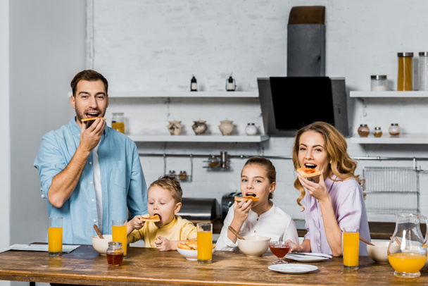 ευτυχισμένη οικογένεια τρώει τοστ με μαρμελάδα στο τραπέζι στην κουζίνα - Φωτογραφία, εικόνα