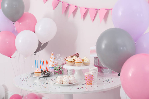 Party treats and items on table in room decorated with balloons - Fotoğraf, Görsel
