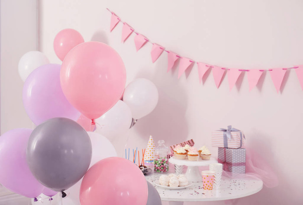 Party treats and items on table in room decorated with balloons - Photo, image
