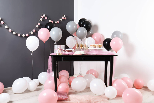 Party treats and items on table in room decorated with balloons - Foto, Imagen