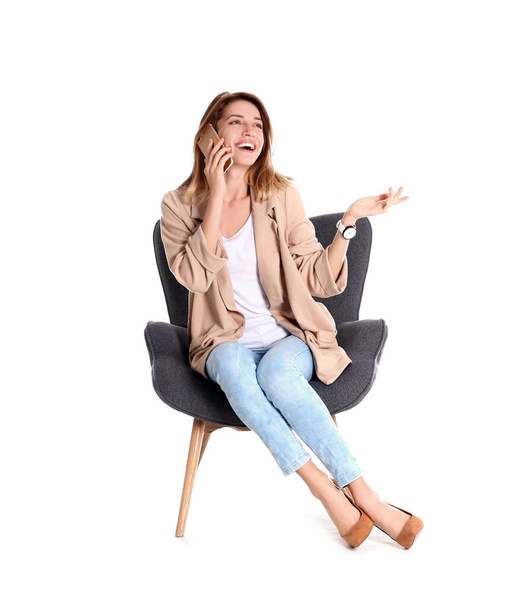 Young woman talking on phone in armchair against white background - Foto, immagini