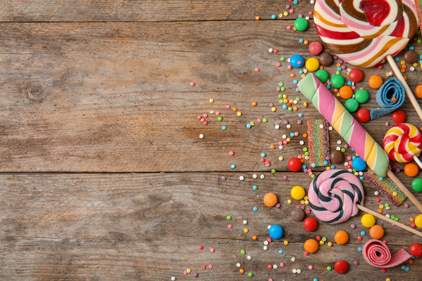 Flat lay composition with different yummy candies and space for text on wooden background - Photo, Image