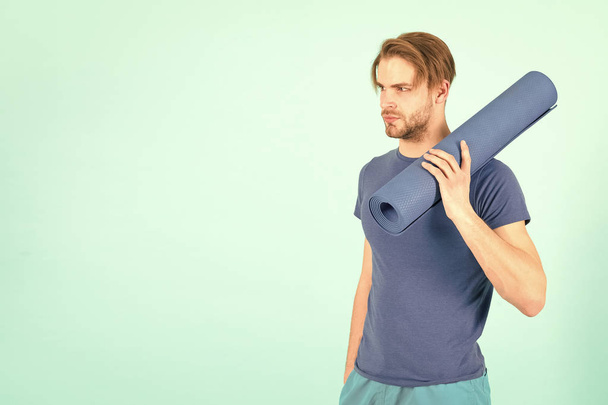 Athlete with blue yoga mat in hand, gym equipment - Zdjęcie, obraz