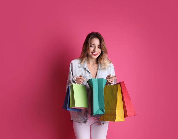 Beautiful young woman with shopping bags on color background - Fotoğraf, Görsel