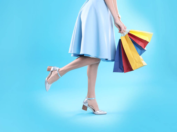 Young woman with shopping bags on color background, closeup of legs - Foto, Imagen