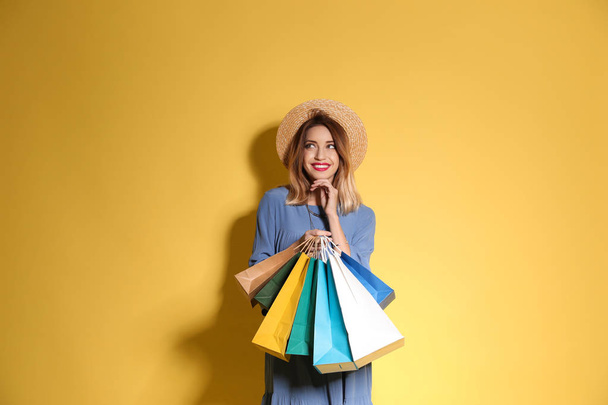 Beautiful young woman with shopping bags on color background - Foto, immagini